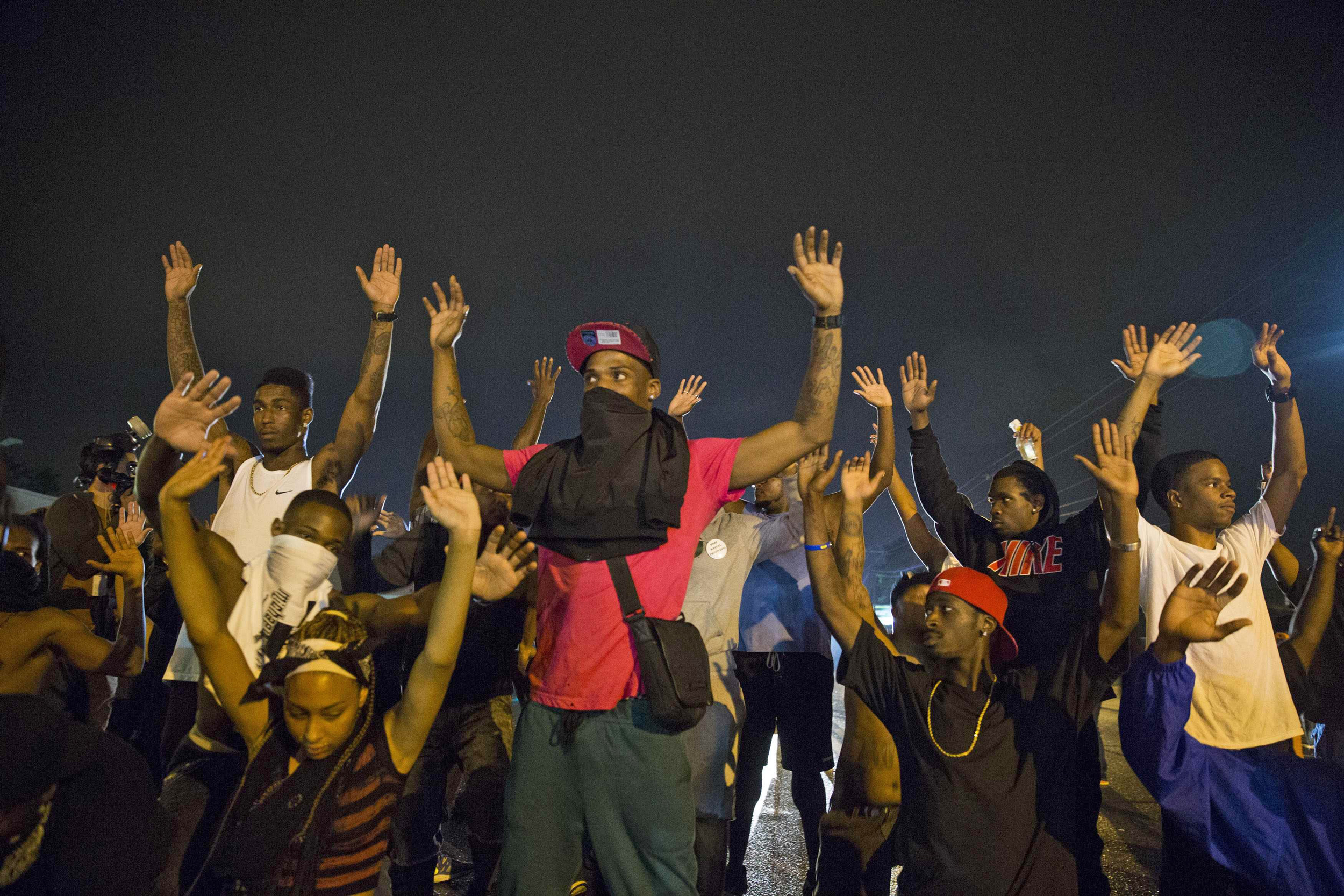 Image: Demonstrators confront police with their arms raised during on-going demonstrations to protest against the shooting of Michael Brown, in Ferguson, Missouri