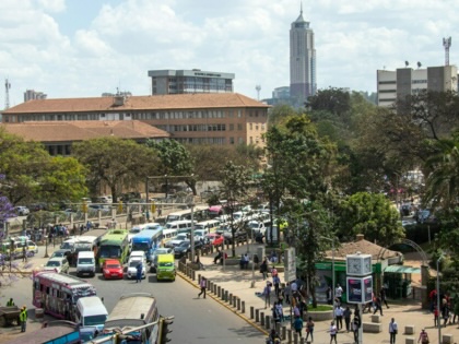 Pedestrians and vehicles move along a busy street in central Nairobi, Kenya, surrounded by commercial buildings and bustling urban activity.
