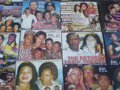 An array of Nigerian film VCDs laid out for sale, with colorful covers.