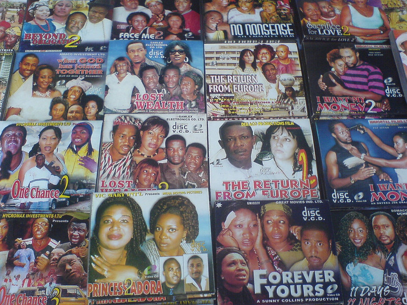 An array of Nigerian film VCDs laid out for sale, with colorful covers.