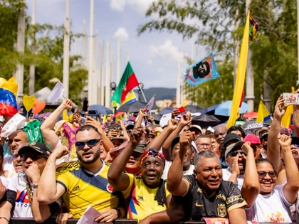 Crowd of demonstrators waving flags and raising their hands during a May Day rally in Medellín, Colombia.