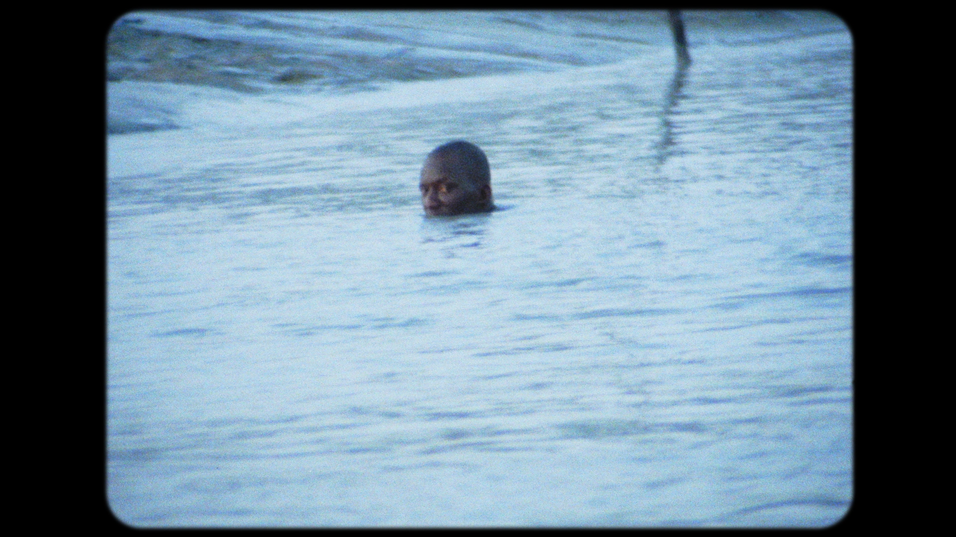 Man in ocean with head above water. 