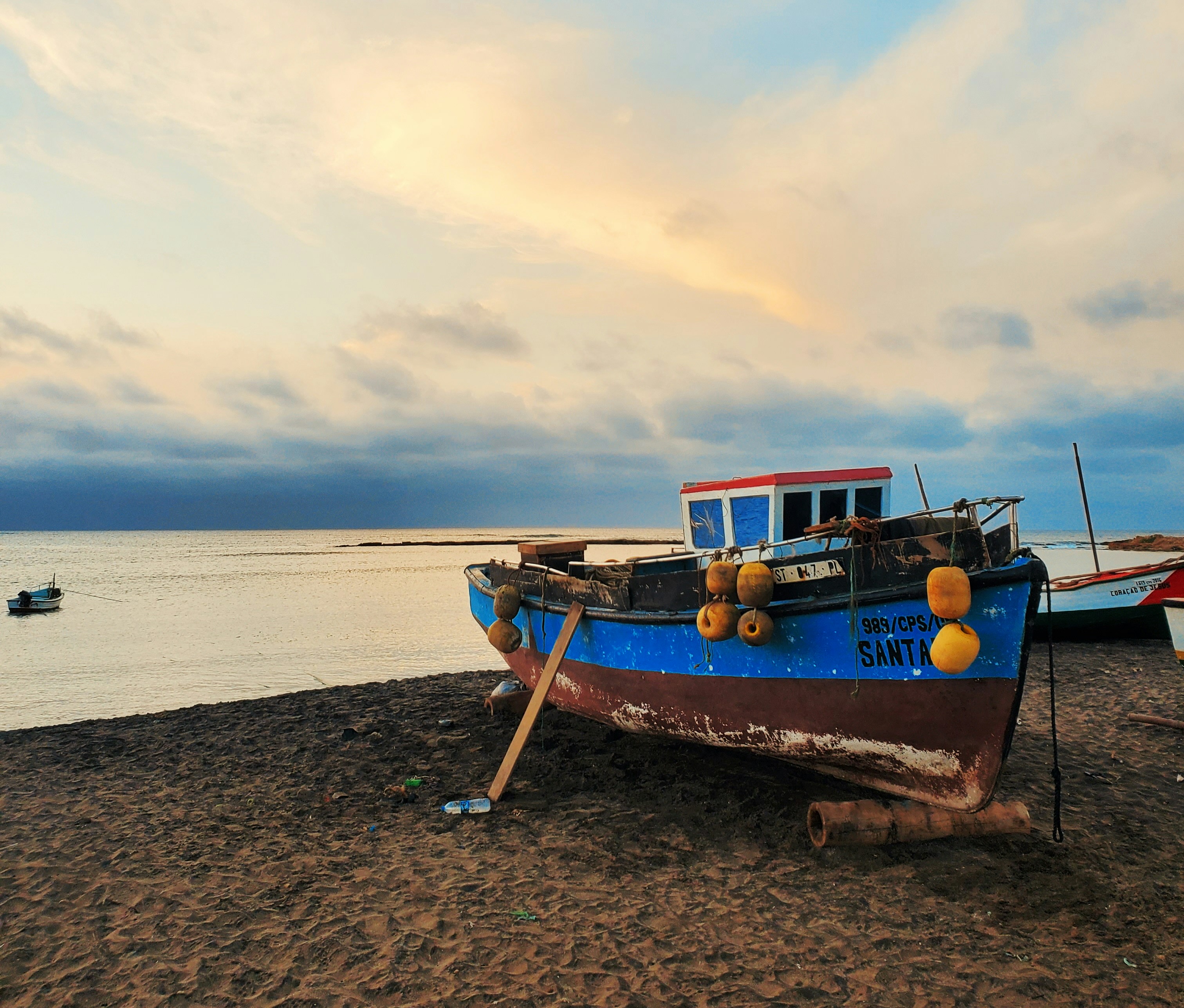 A colorful fishing boat resting on the coastline in Maio, Cape Verde.