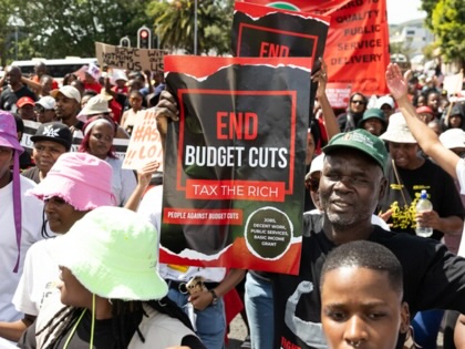 Protestors carrying placards and banners on a march outdoors.