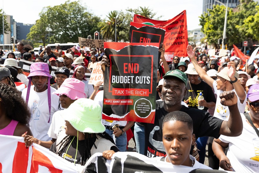 Protestors carrying placards and banners on a march outdoors.
