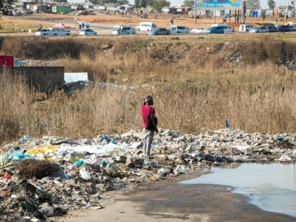 A person standing in a puddle of water in a landfill