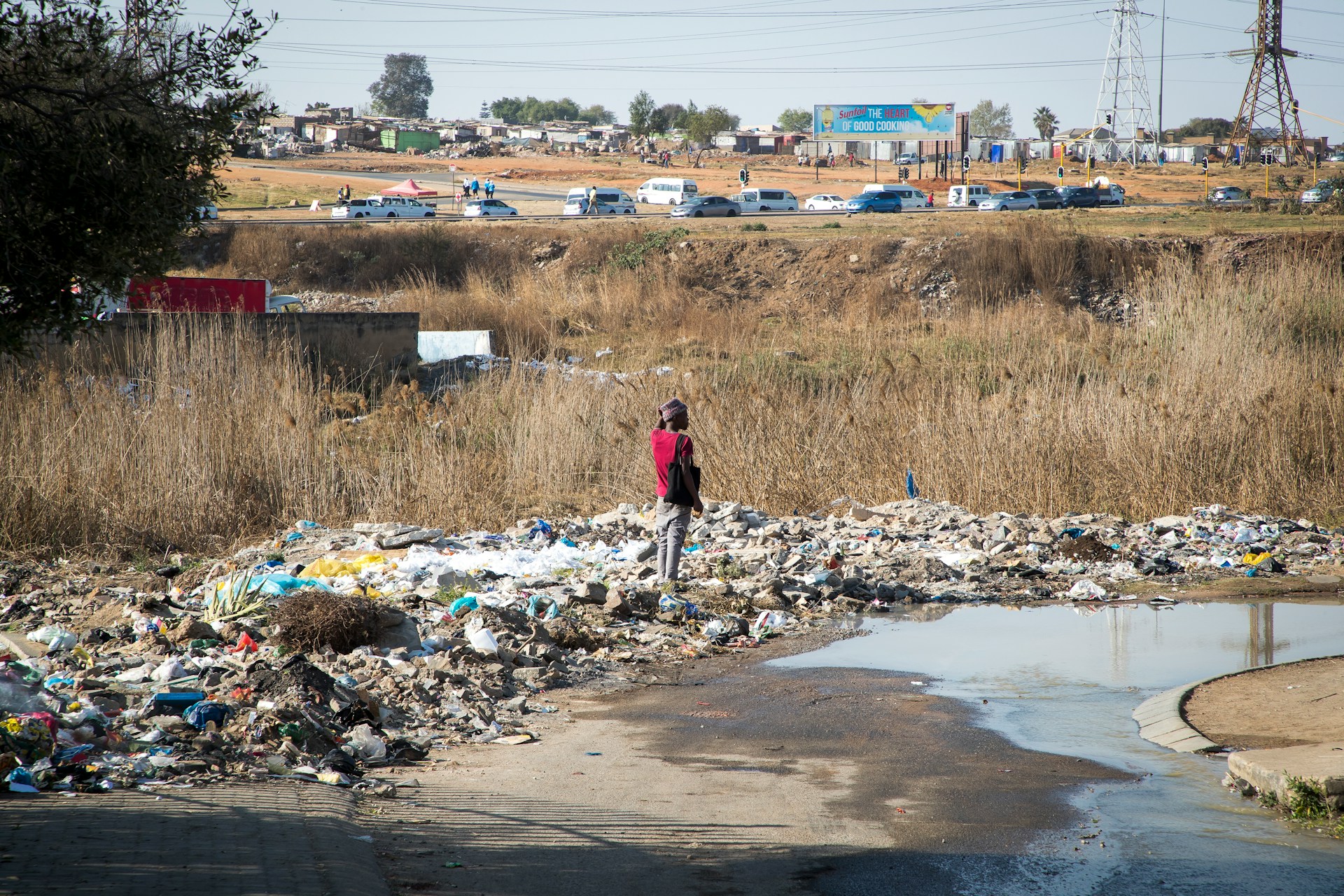 A person standing in a puddle of water in a landfill