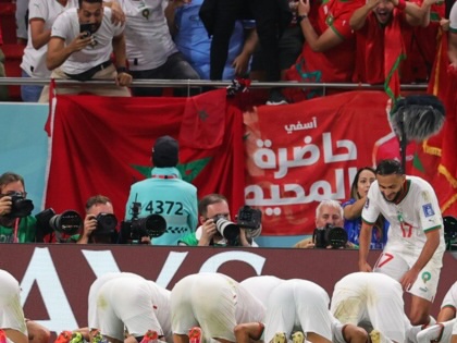 A group of football players dressed in white kneeling on the ground in a football stadium.