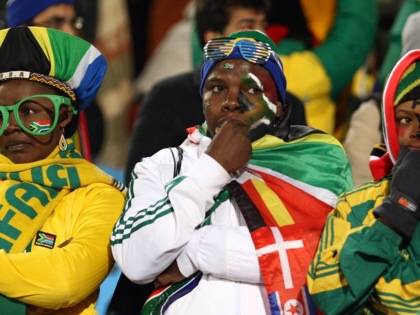 Three South African football supporters dressed in national colours sit silently in the stands, appearing dejected during a 2010 FIFA World Cup match against Uruguay.