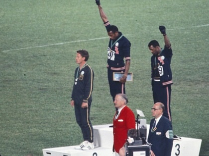 Olympic medallists Tommie Smith, Peter Norman, and John Carlos stand on the podium after the 200 metres at the 1968 Mexico City Olympics. Smith and Carlos bow their heads and raise black-gloved fists in protest against racial discrimination.