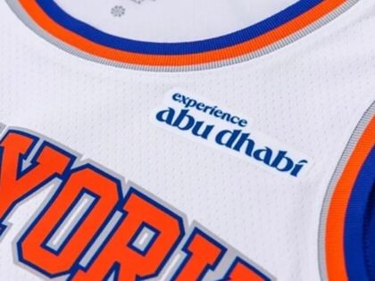 Close-up of a New York Knicks basketball jersey displaying the “Experience Abu Dhabi” sponsor patch above the team name.