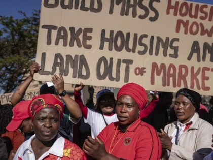 Abahlali baseMjondolo members march with a large placard reading “Build mass housing now! Take housing and land out of market” during a protest against proposed changes to South Africa’s eviction laws.