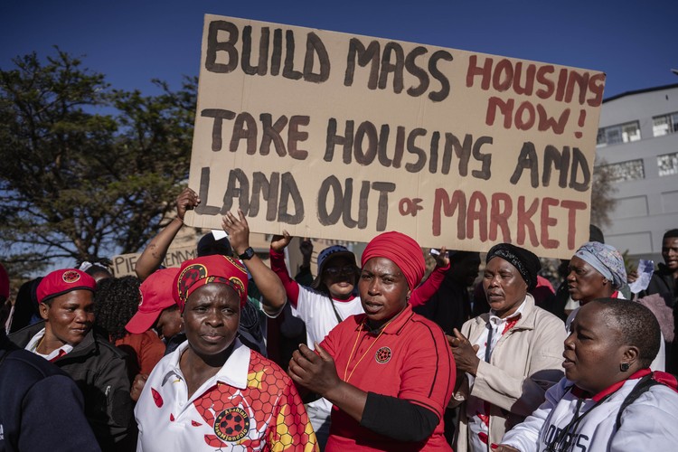 Abahlali baseMjondolo members march with a large placard reading “Build mass housing now! Take housing and land out of market” during a protest against proposed changes to South Africa’s eviction laws.
