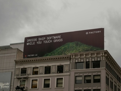 A billboard on a building in San Francisco, California, depicts an advertisement reading, "Droids ship software while you touch grass"