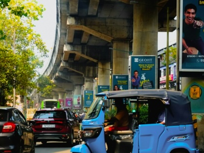 A rickshaw passes by an expressway bridge in India.