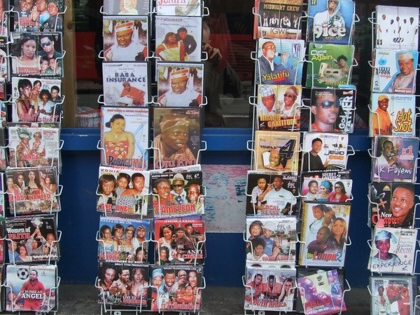 Racks of Nollywood DVD covers displayed outside a shop in Dalston, London, featuring dozens of Nigerian films in colorful packaging.