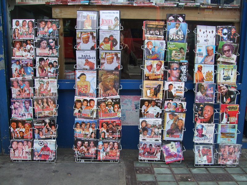 Racks of Nollywood DVD covers displayed outside a shop in Dalston, London, featuring dozens of Nigerian films in colorful packaging.
